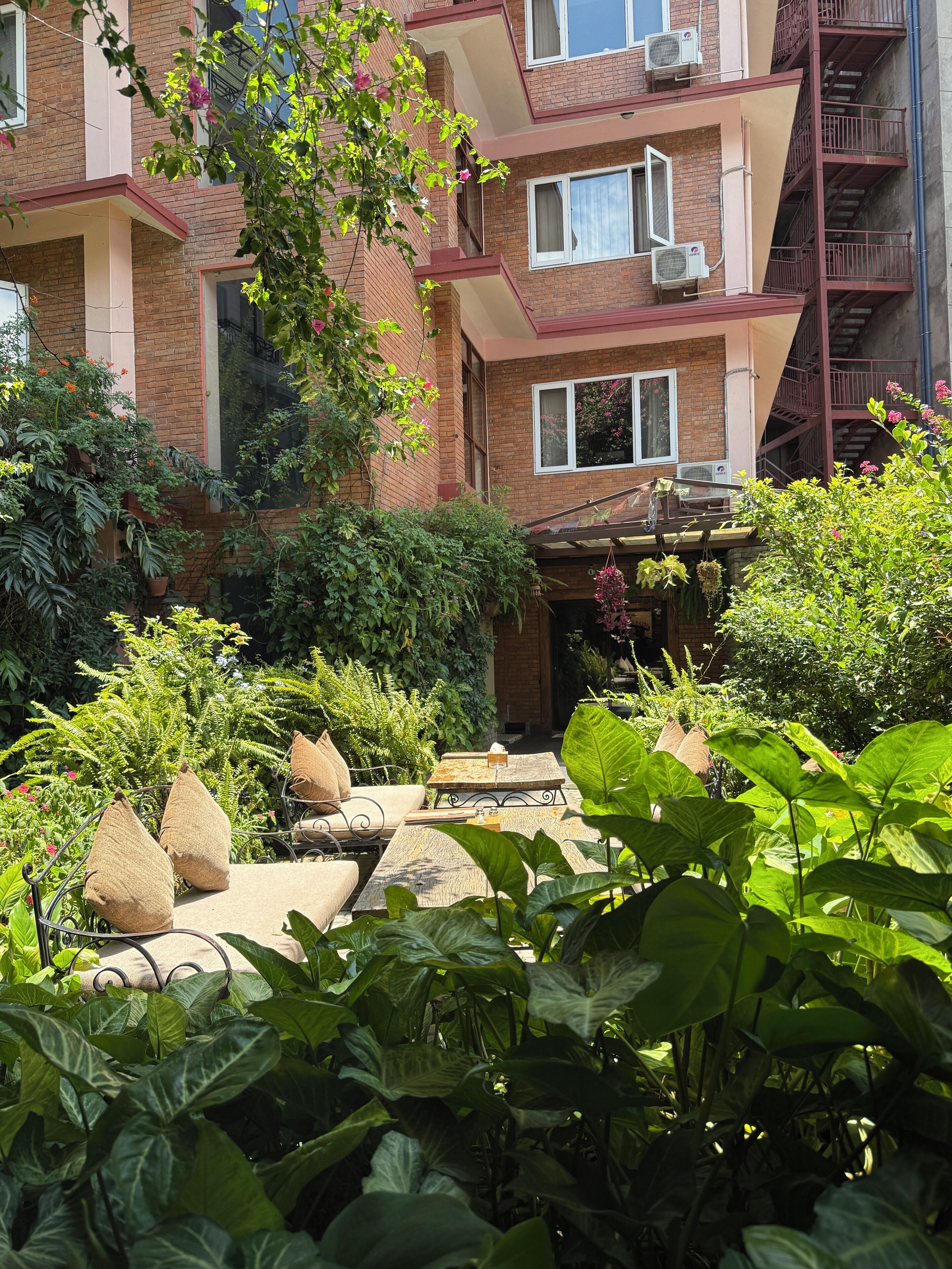 A multi-story building with a brick facade, air conditioning units, and a balcony.