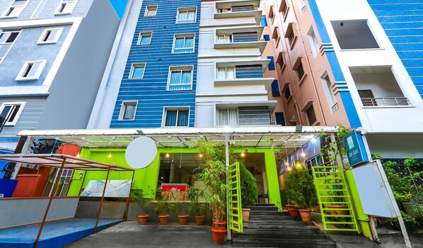 A multi-story building with balconies, a covered entrance area with potted plants, and a signboard. - Hotel Blue Dawn - Near DLF Cyber City, Gachibowli (Hyderabad)