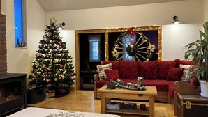 A cozy living room with a Christmas tree, a red sofa, a wooden coffee table, and a fireplace.