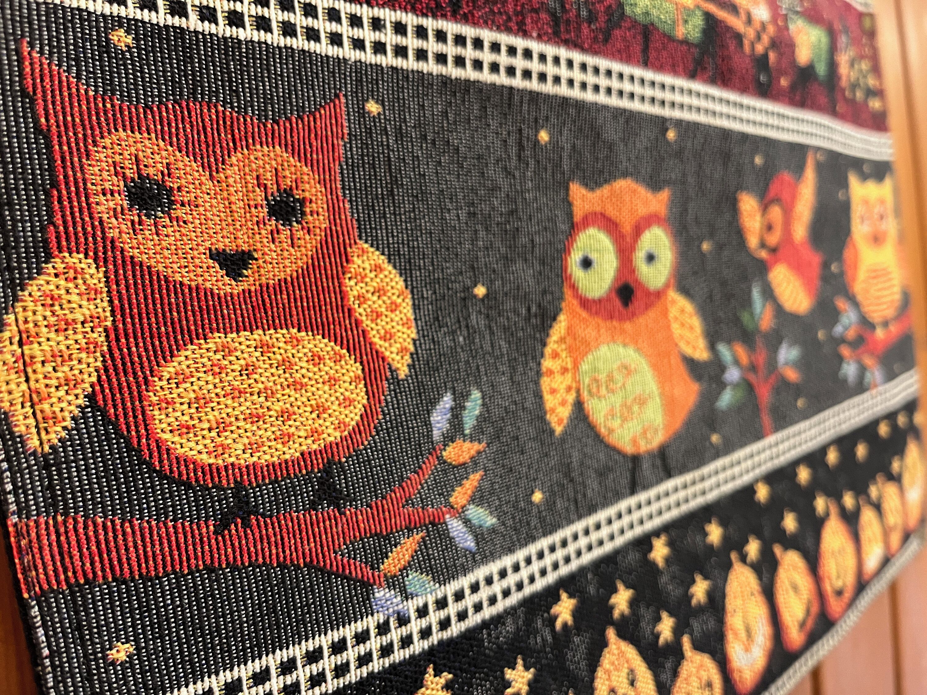 Un gros plan d’une œuvre d’art réalisée au point de croix, représentant un chat et des hiboux.