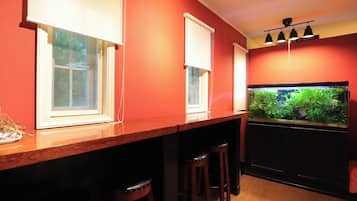 A bar area with a fish tank, wooden bar stools, and a red wall.