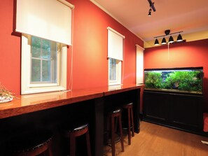 A bar area with a fish tank, wooden bar stools, and a red wall. - Julian's (Fujimi)