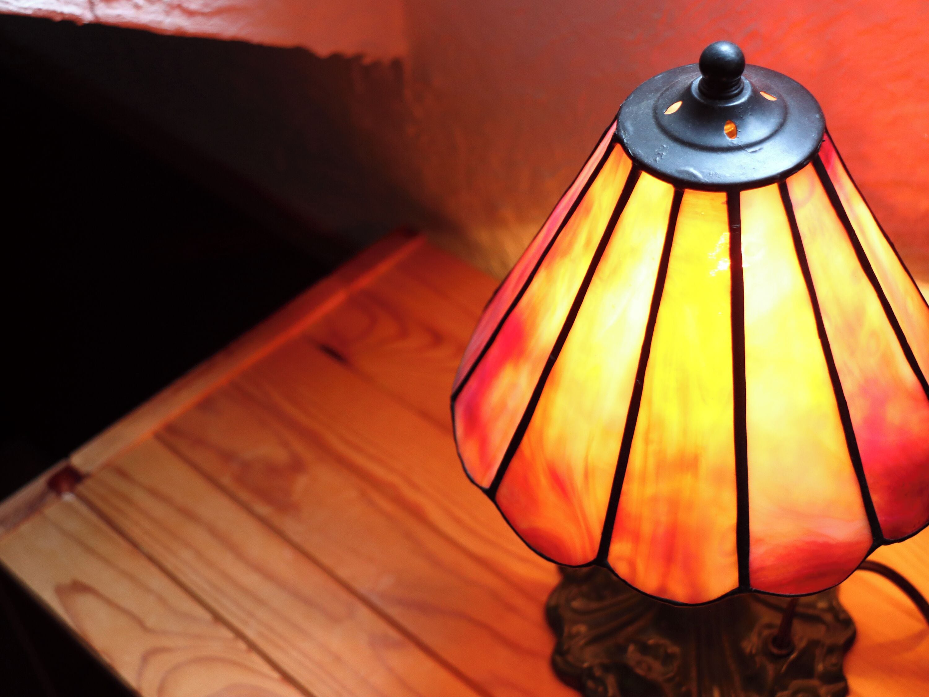 Een tafellamp met een decoratieve voet en een glazen kap met verticale strepen.