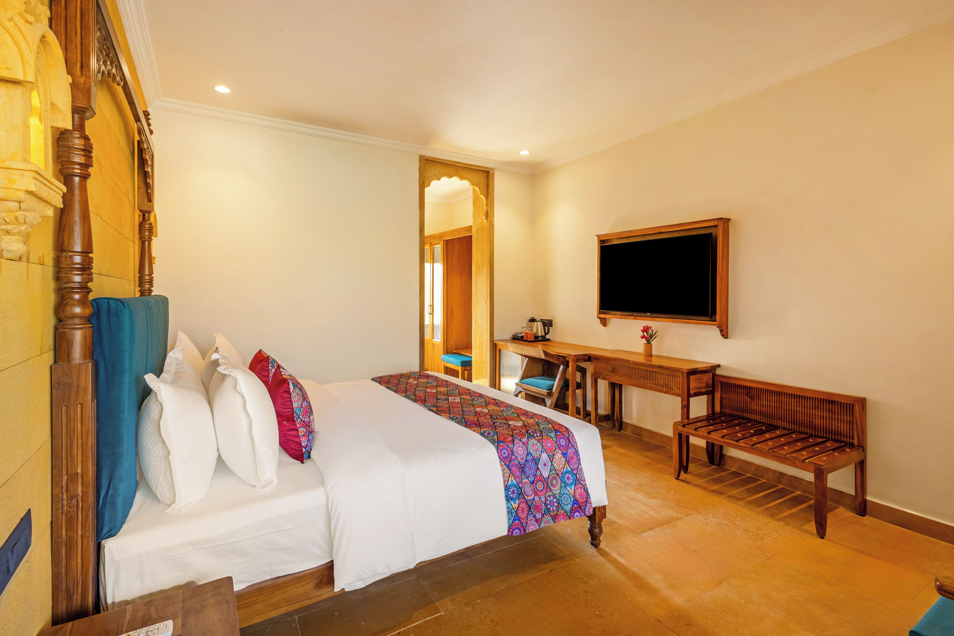 Ein Hotelzimmer mit einem großen Bett, einem Schreibtisch, einer Bank und einem Fernseher.
