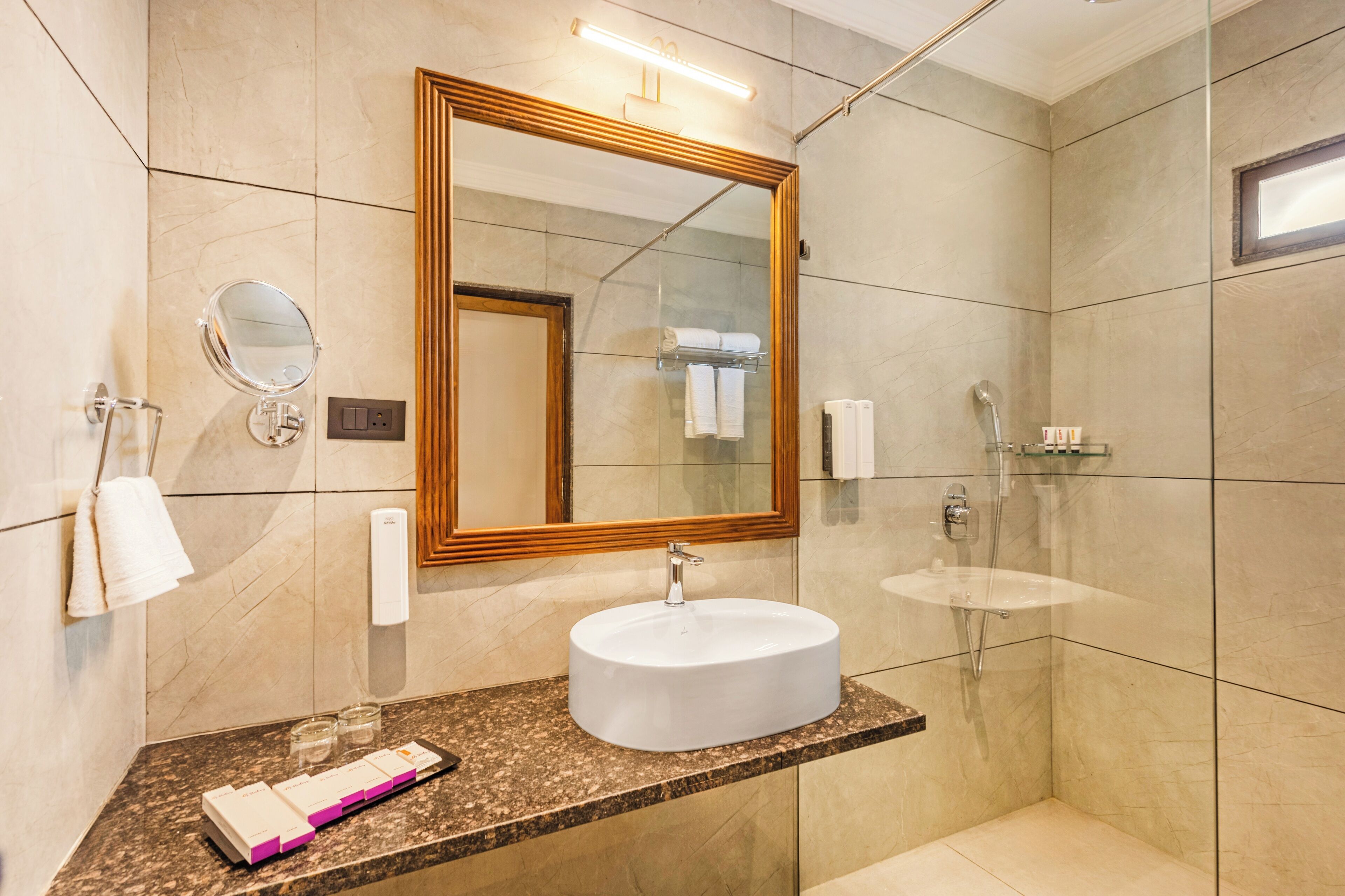 A modern bathroom with a round sink, a large mirror, and a shower area.