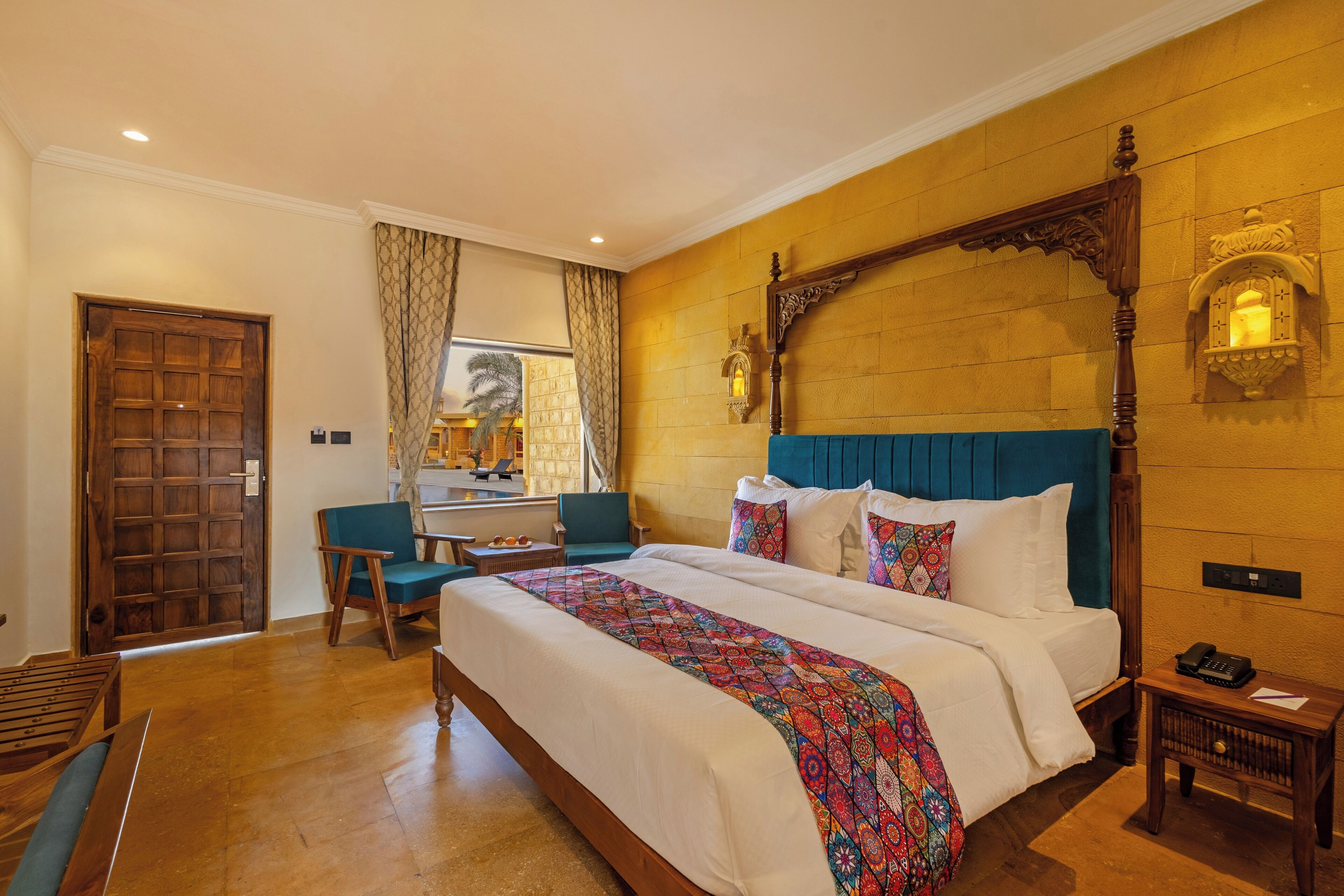 Une chambre d’hôtel avec un grand lit, un bureau, une chaise et une porte en bois.