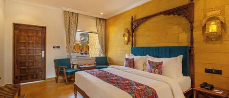 Una habitación de hotel con una cama grande, un escritorio, una silla y una puerta de madera.