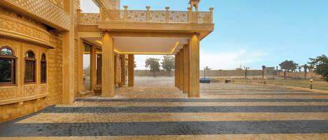 A courtyard with a covered walkway, ornate architectural details, and a clear sky.