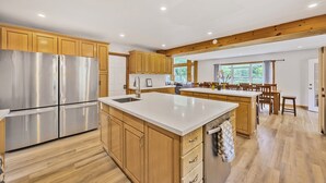 A spacious kitchen with wooden cabinets, a large stainless steel refrigerator, and a central island with a sink.