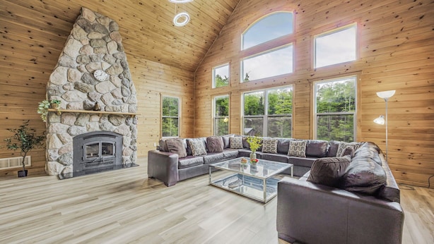A spacious living room with a stone fireplace, large windows, and a modern sofa set.