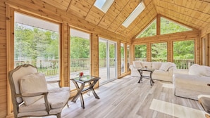 A spacious wooden interior with large windows, a ceiling fan, and a balcony with a view of greenery.