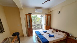 A hotel room with a bed, a desk, and a balcony. - Dsouzas Guest House (Bardez)