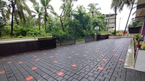 A paved walkway with a black and red tile pattern, surrounded by greenery and palm trees. - Dsouzas Guest House (Bardez)