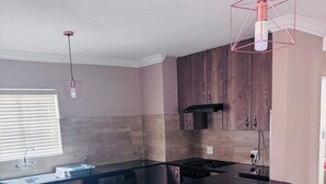 A modern kitchen with a central island, bar stools, and pendant lighting.