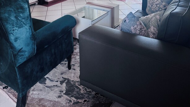 A living room with a sofa, a coffee table, a TV, and a window with curtains.