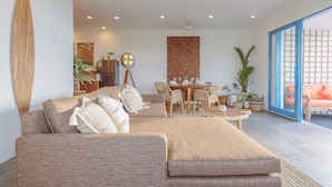 Een moderne woonkamer met een grote hoekbank, een eethoek en uitzicht door een glazen deur.