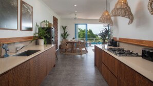 Een moderne keuken met een centraal eiland, houten kastjes en hanglampen.