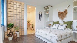 Een slaapkamer met een bed, een witte inbouwkast, een nachtkastje en een macramé wanddecoratie.