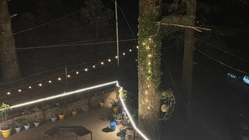 Een terras buiten met lichtslingers, planten in potten en een zithoek.