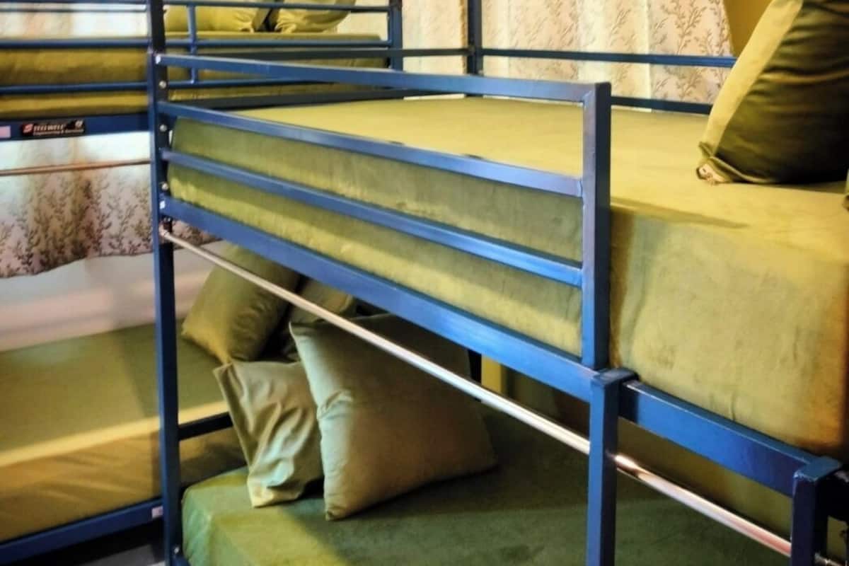A bunk bed room with two beds, green bedding, and floral curtains.
