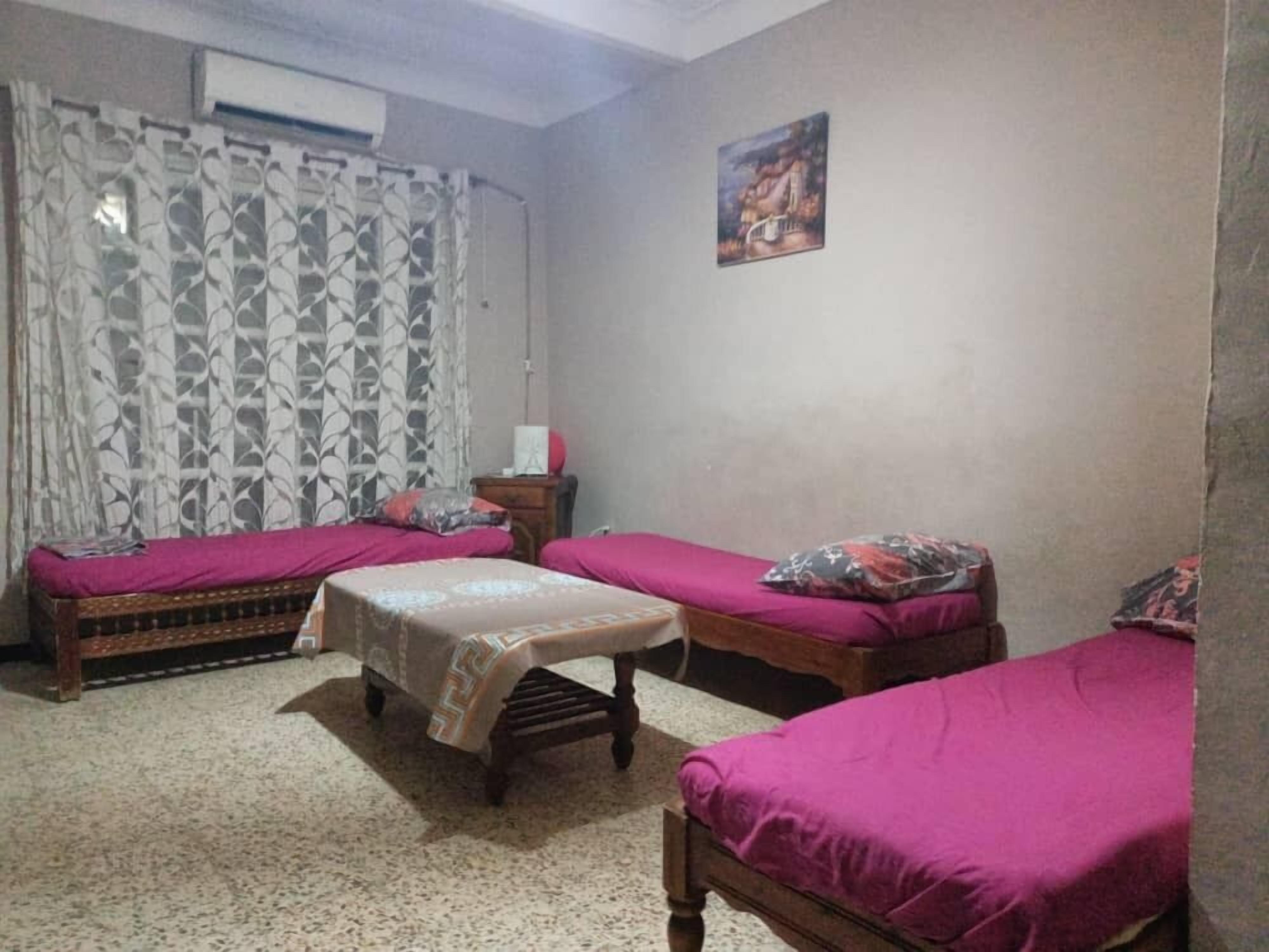 A room with two beds, a small table, and a curtain.