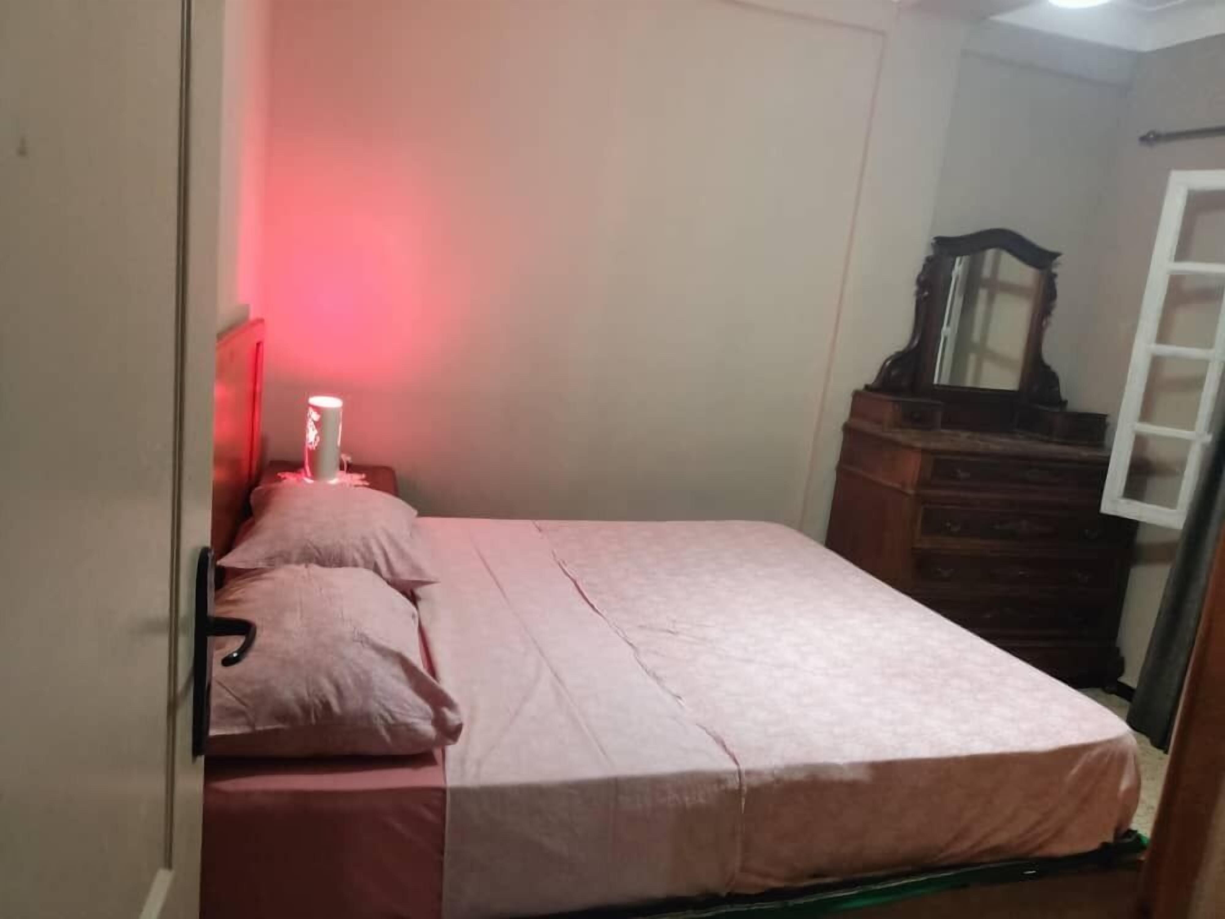 Un dormitorio con cama, mesita de noche, cómoda y espejo.