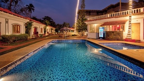 Una piscina con bordes de azulejos, rodeada de edificios con techos rojos y palmeras.