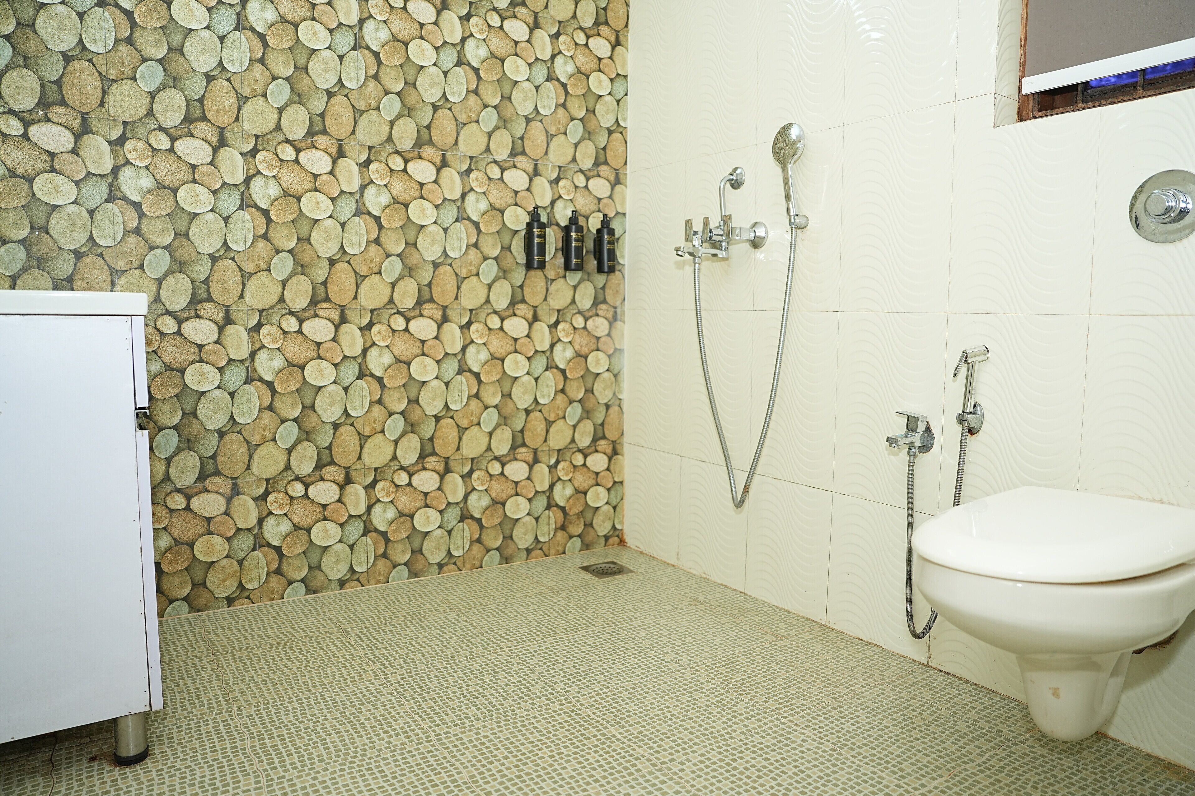 A bathroom with a mosaic wall, a toilet, and a shower.