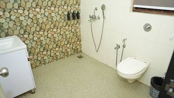 A bathroom with a mosaic wall, a toilet, a sink, and a trash bin.