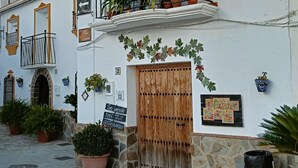 A building with a wooden door, stone walls, and potted plants.