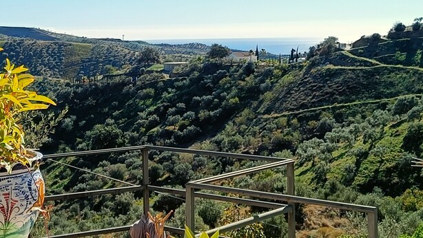 A scenic view from a balcony overlooking a hilly landscape with a clear sky.