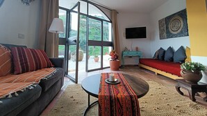 A living room with a sofa, a coffee table, a TV, and a sliding glass door leading to a balcony.