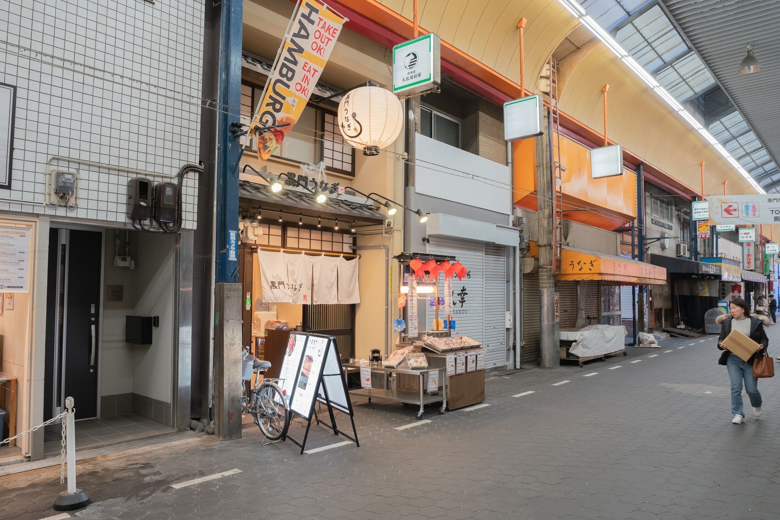 Een straat met verschillende winkels, waaronder een restaurant met een bord waarop 