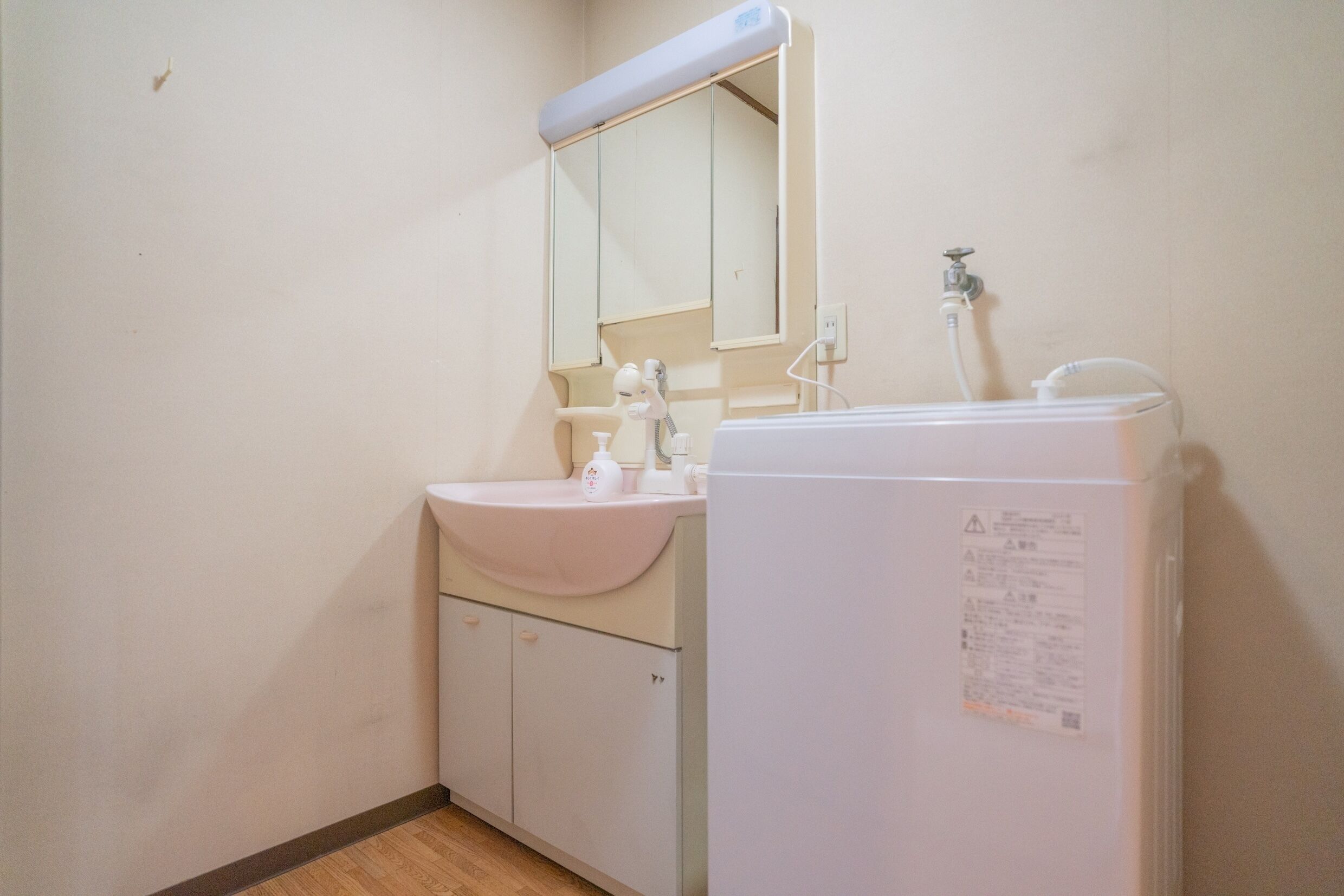 A small bathroom with a sink, mirror, and a white refrigerator.