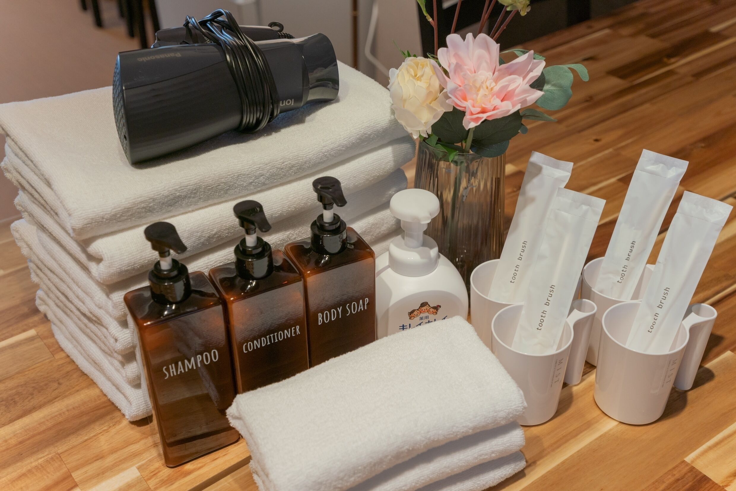 A neatly arranged bathroom with toiletries including shampoo, conditioner, body soap, and toothbrushes.