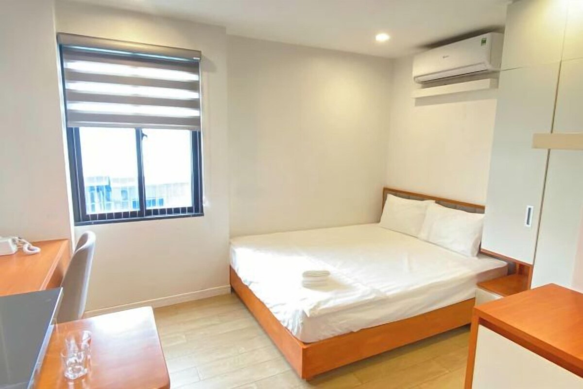 Una habitación pequeña y limpia con una cama individual, un escritorio y una ventana con persianas.