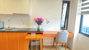 Una cucina con zoccolo in marmo, piano di lavoro in legno, lavandino, un vaso con fiori, una finestra con persiane e una sedia.