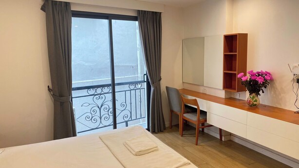 Una camera d'albergo con un letto, una scrivania, una sedia, uno specchio e una finestra con tende.