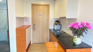 Una cucina compatta con una porta in legno, un piano di lavoro e un vaso con fiori rosa.