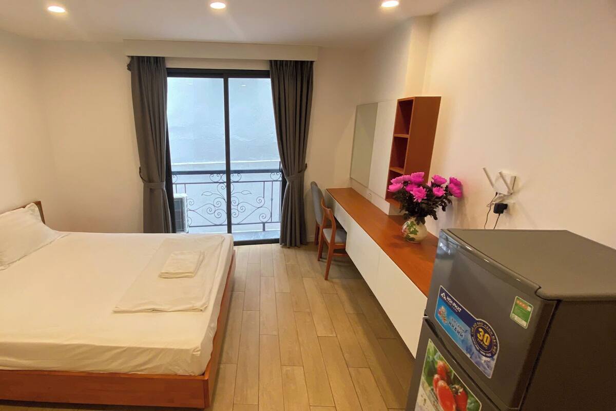 Une chambre d’hôtel équipée d’un lit, d’un bureau, d’un mini-bar et offrant une vue sur l’extérieur.