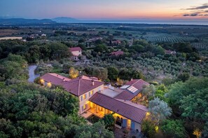 A large estate with multiple buildings, surrounded by dense vegetation and fields.