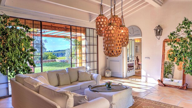 A spacious living room with a large sofa, a coffee table, and a view of the outdoors through large windows.