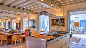 A modern kitchen with a central island, stainless steel appliances, and a dining area with wicker chairs.