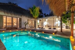 A pool area with a thatched-roof structure, lounge seating, and a well-lit interior space. - Lempuyang Boutique Hotel (Karangasem)