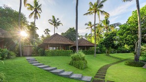 A tropical resort with thatched-roof huts, a well-manicured lawn, and palm trees. - Lempuyang Boutique Hotel (Karangasem)