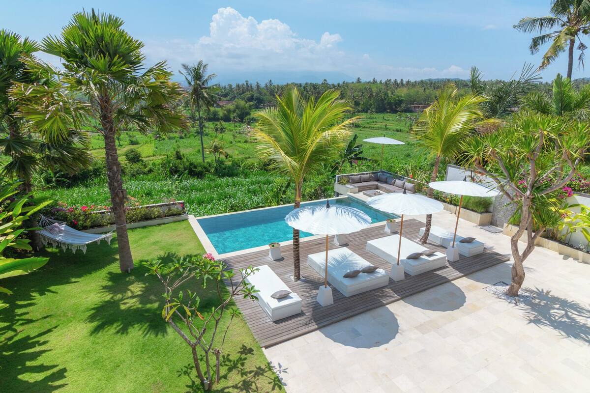 A private pool area with a wooden deck, lounge chairs, and umbrellas.