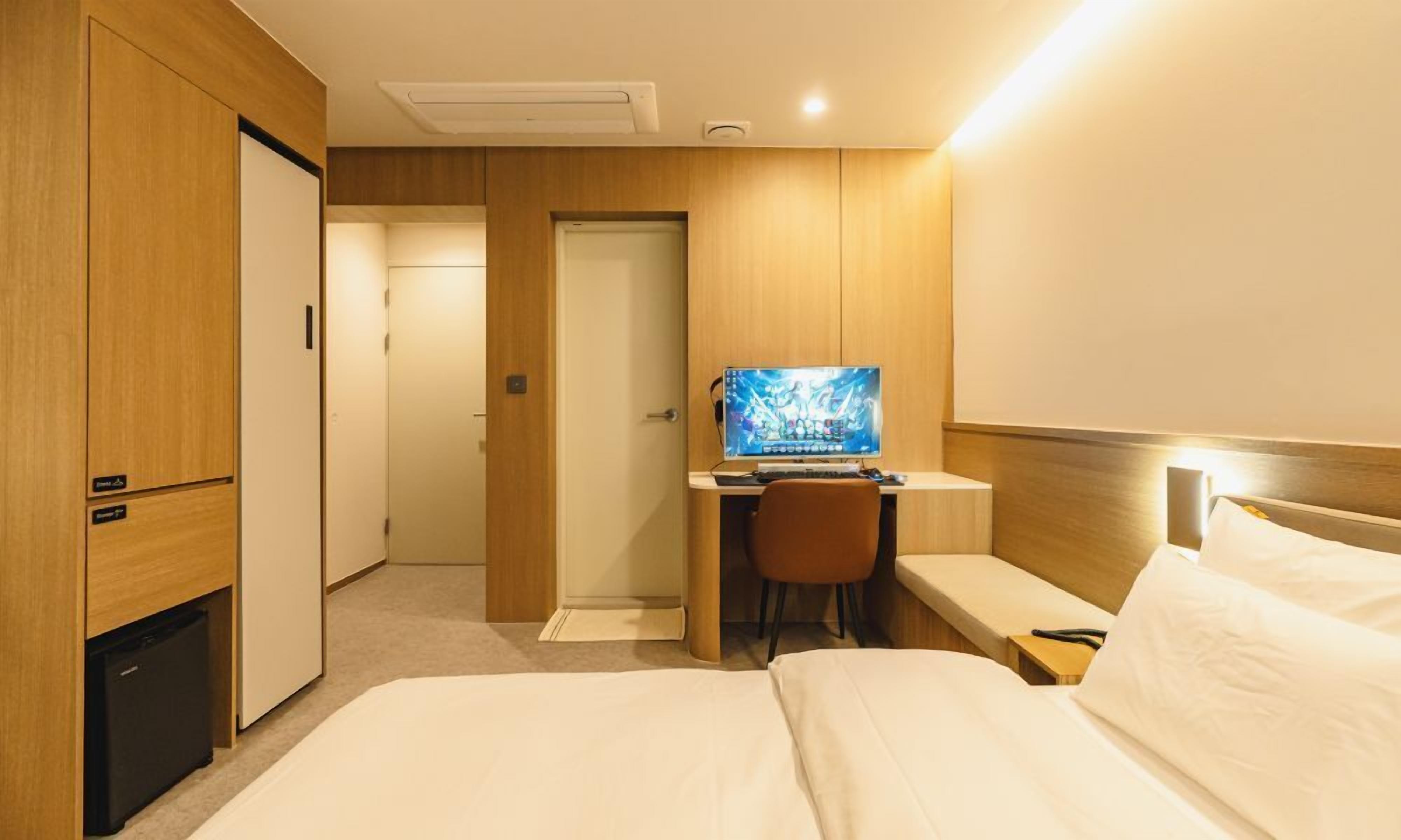 Een hotelkamer met een bed, een bureau met een computer, een stoel en een televisie.