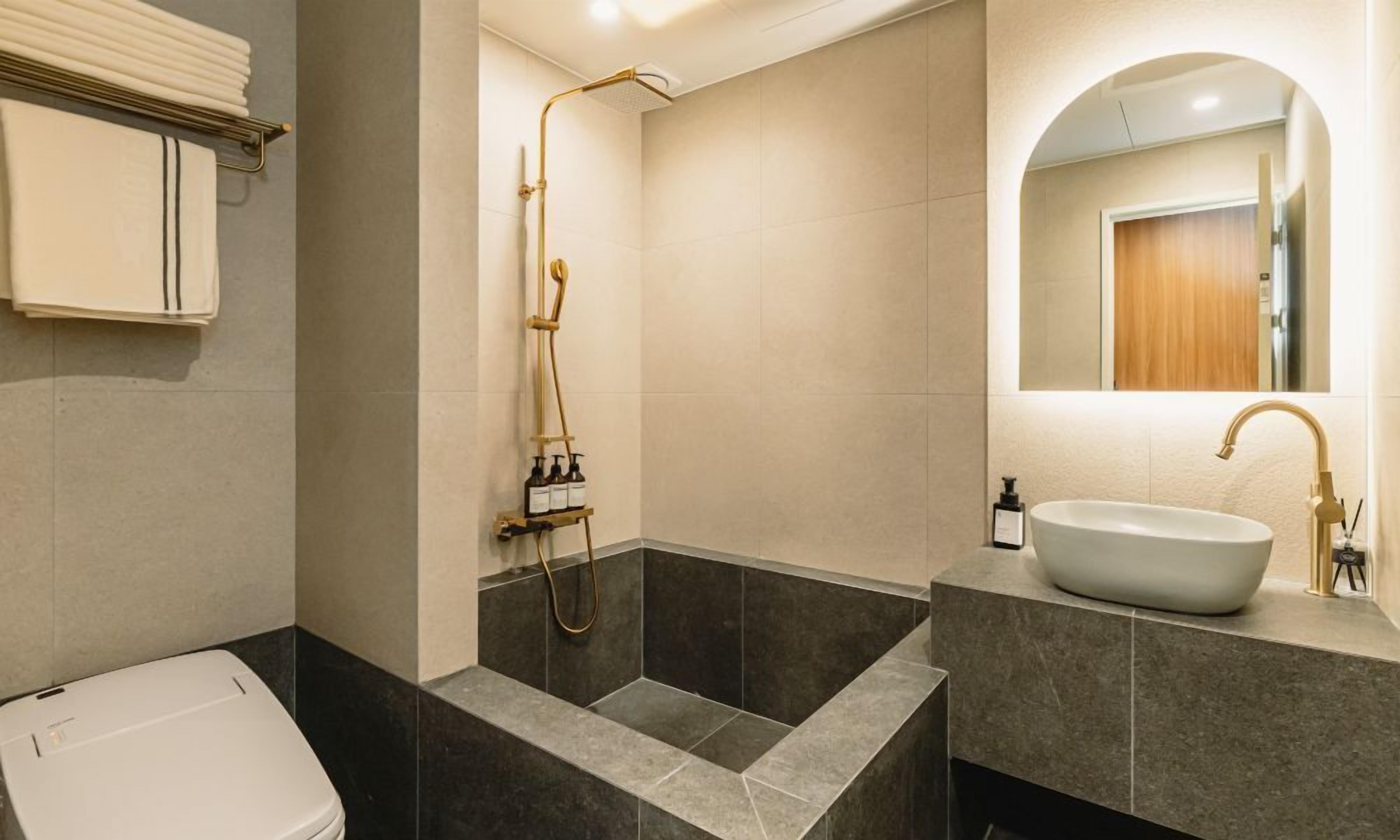 A modern bathroom with a freestanding bathtub, a large sink, and a shower with a gold faucet.