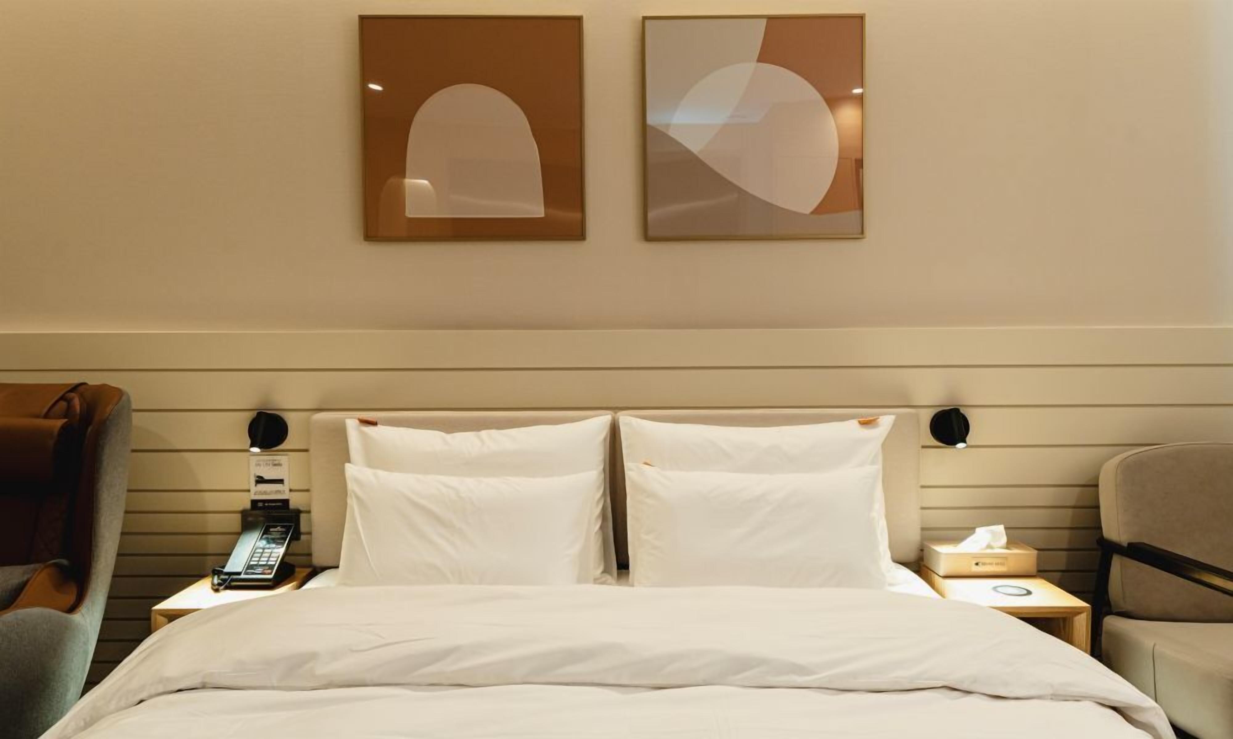 A hotel room with a bed, two bedside tables, a telephone, and a chair.