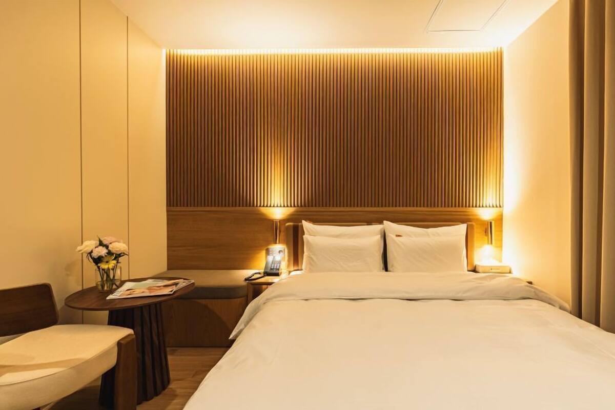 A hotel room with a large bed, bedside tables, a small desk, and a chair.
